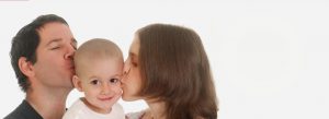 a couple kissing their cancer sick child